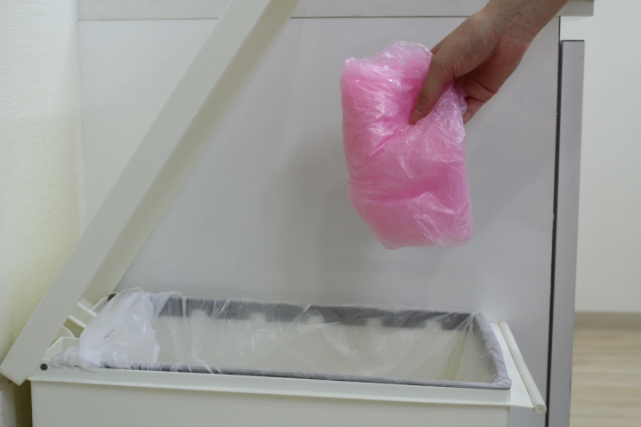 使用後のエプロンを小さくまとめてゴミ箱に捨てる様子