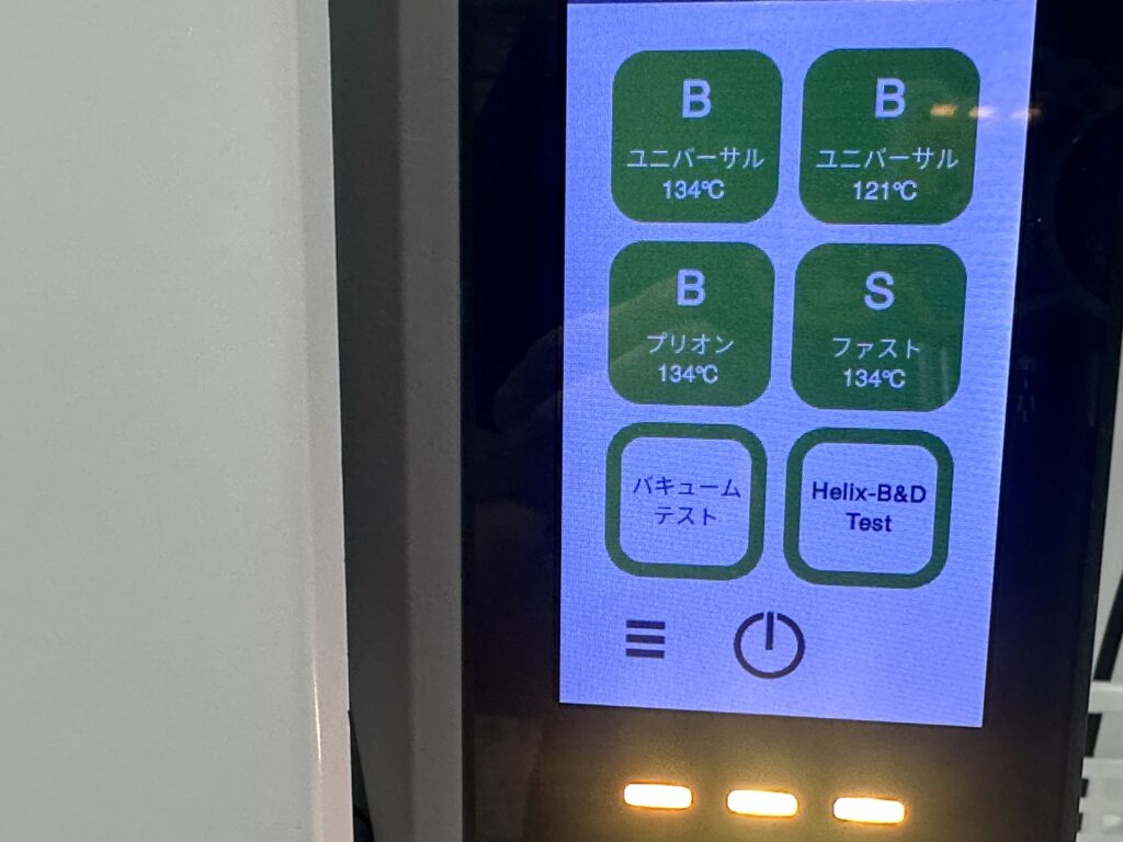クラスB滅菌器の操作パネル。Bユニバーサル134℃などのプログラムと並んで、バキュームテストとHelix-B&D Testのボタンが表示されている。