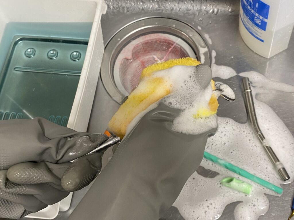 厚手の手袋をつけてスケーラーをブラシで洗浄しているところ