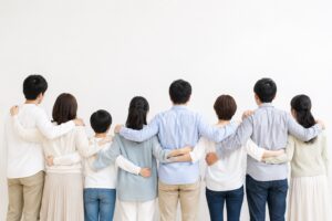 年齢のちがう人たちが肩を組んで並ぶ後ろ姿（標準予防策＝すべての人に同じ対応をする）