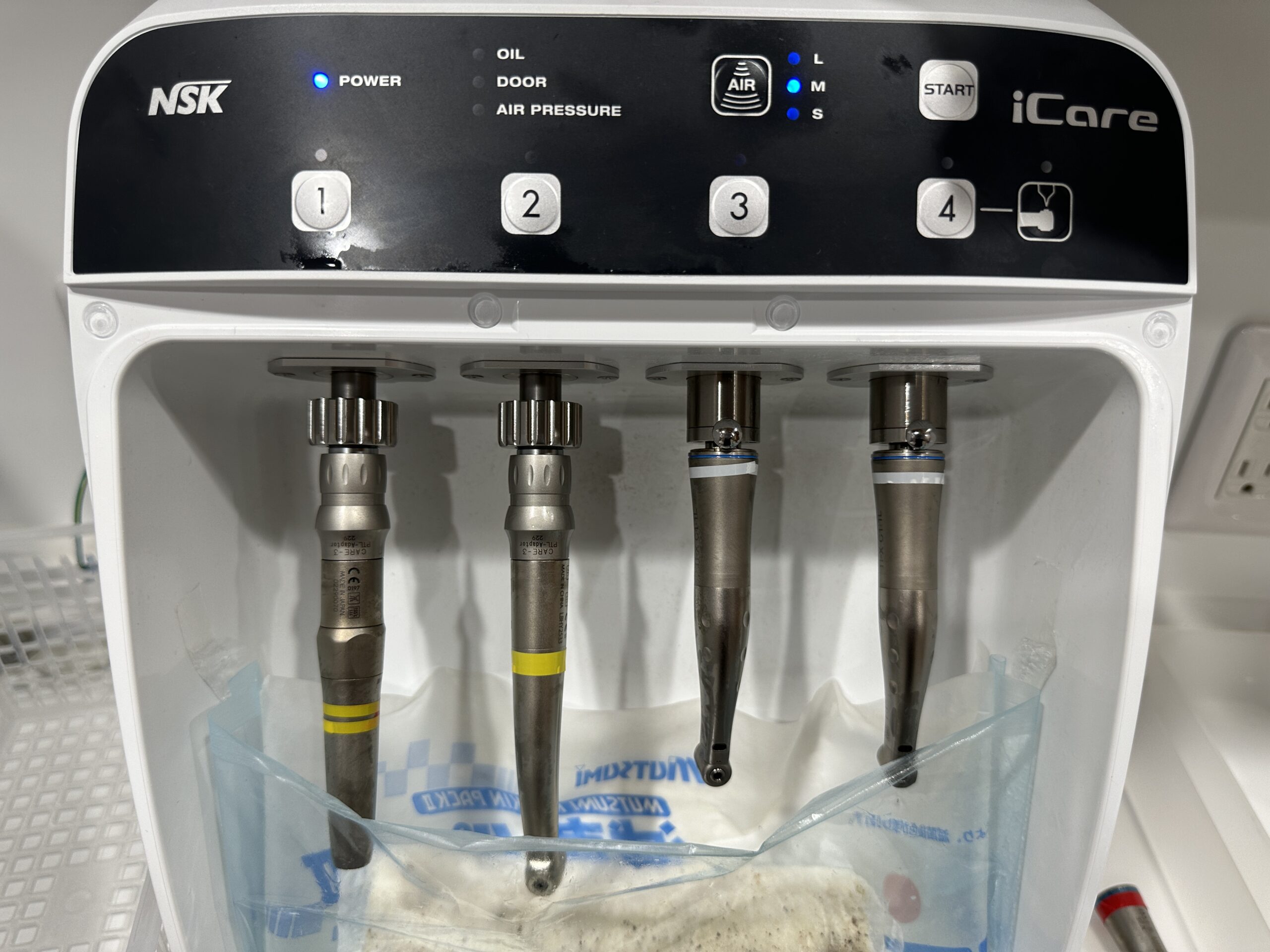 自動注油器にセットされた4本のハンドピース。注油は洗浄のあとに行う、機械のための工程
