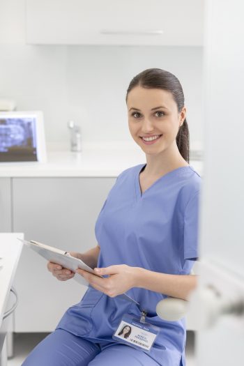 Portrait of confident smiling nurse with clipboard at dental clinic
